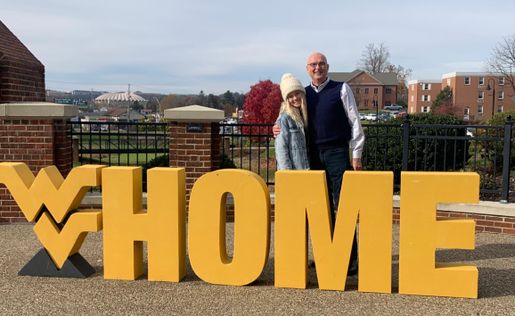 Rachel Morgan, a sophomore marketing student, poses with the WVU Home sign outside the WVU Alumni Center